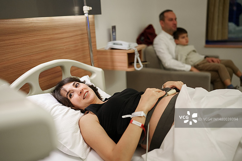 在医院接受监护的孕妇，与心电图和注射分娩和药物相连图片素材