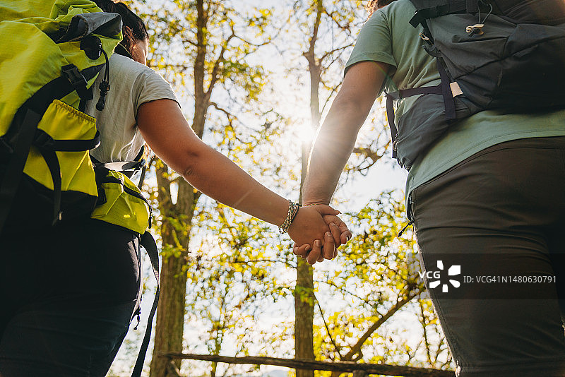 一对情侣在森林里徒步时手牵着手的细节图片素材