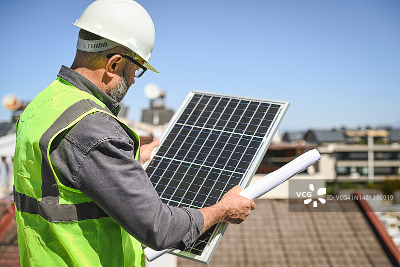 工人在屋顶上安装太阳能电池板图片素材