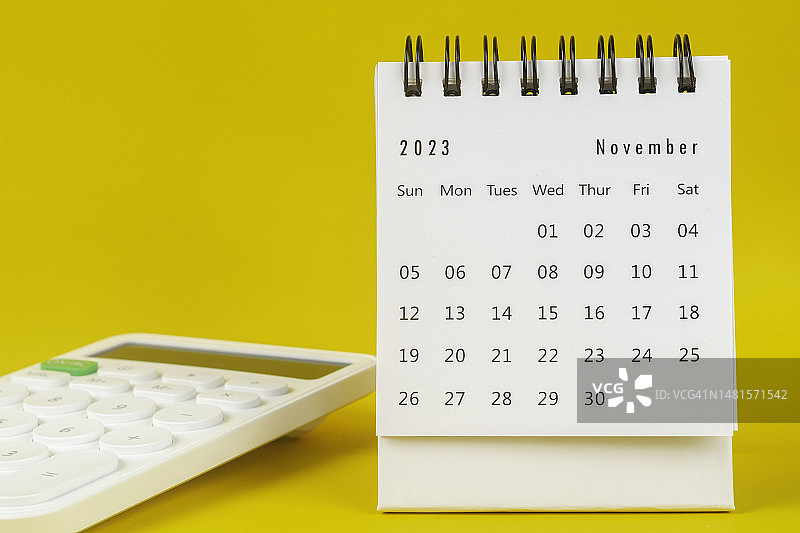 日历台2023:11月是组织者用黄色纸张背景下的白色计算器来计划和截止日期的月份。图片素材