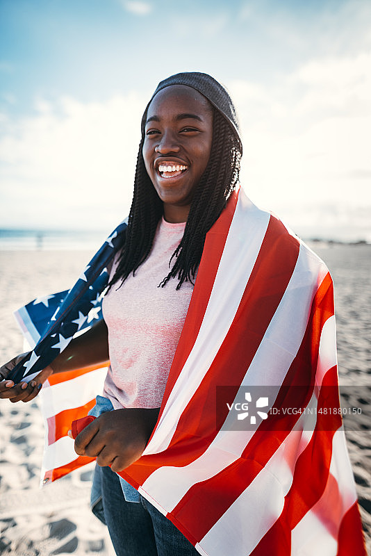 一名非洲妇女在海滩上举着美国国旗图片素材