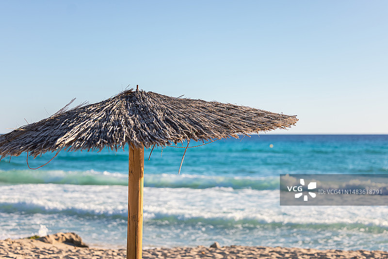 沙滩上的阳伞，蓝色的大海在背后。图片素材
