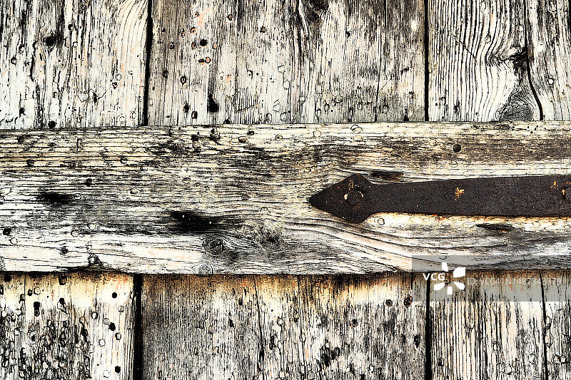 乡下谷仓上了锁的旧木门。木板和生锈的铁钉的纹理。古建筑紧闭的门。被遗弃、被遗忘、摇摇欲坠的建筑。图片素材