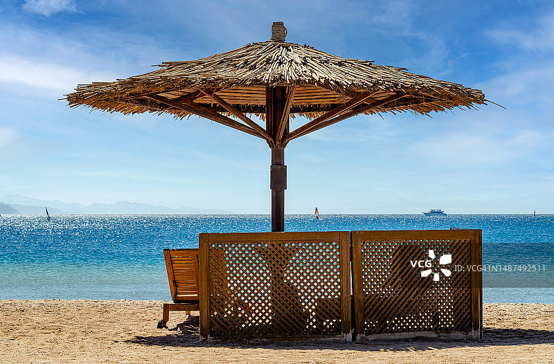 埃及红海岸边的草编沙滩伞和椅子图片素材
