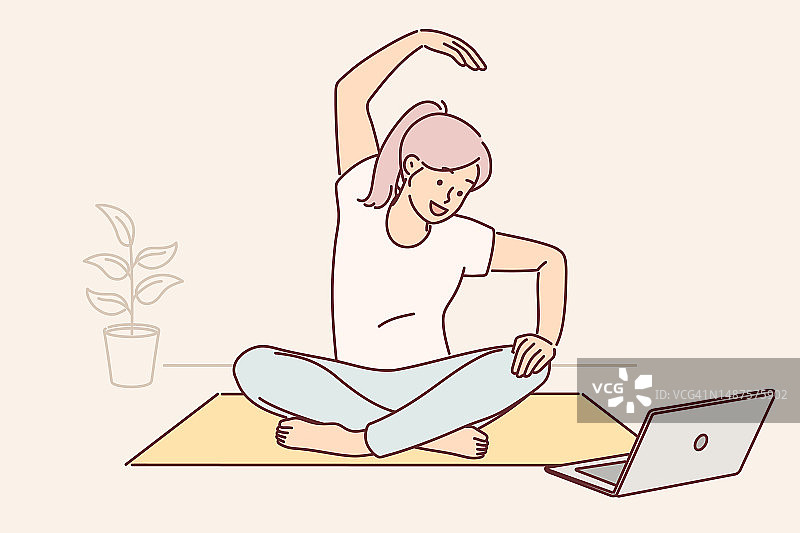 一名女子坐在瑜伽垫上，看着笔记本电脑屏幕，在网络广播期间做练习图片素材