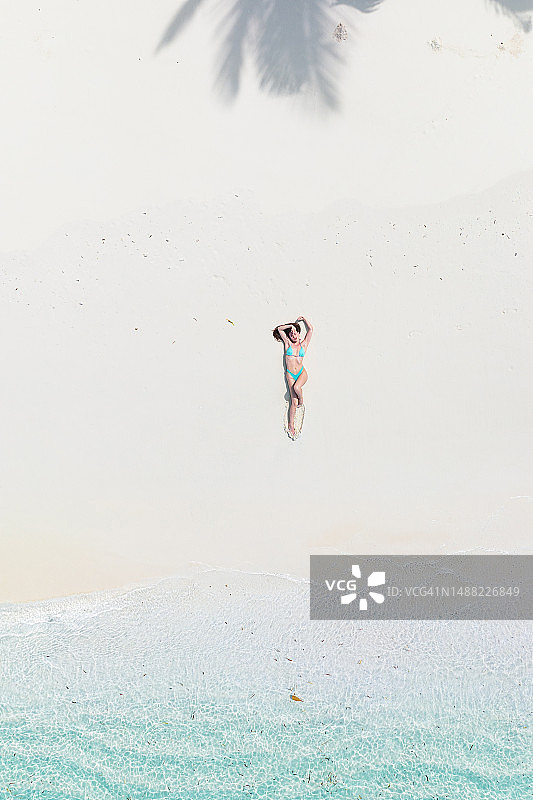无人机拍摄的一名女子躺在沙滩上图片素材