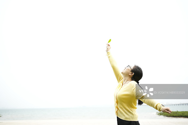 女人很高兴地举起叶子看图片素材