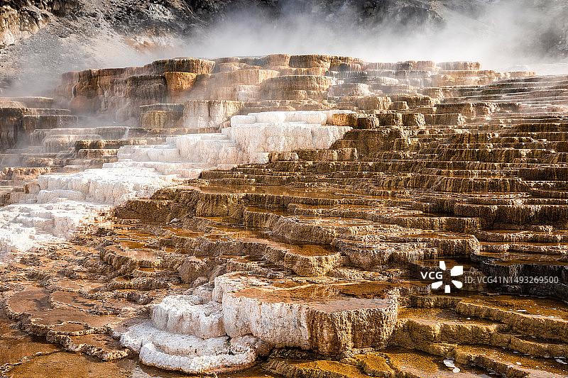 由烟雾覆盖的碳酸钙形成的猛犸温泉梯田，黄石国家公园，美国怀俄明州图片素材