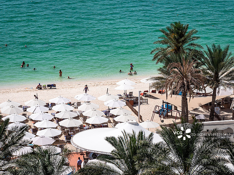阿联酋迪拜——迪拜滨海海滩远处的景色，海浪拍打着沙滩，人们放松地晒着日光浴图片素材