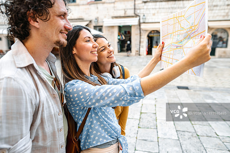 三个年轻的游客在探索城市的同时看着地图图片素材