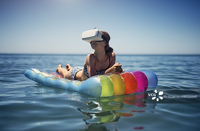 女孩放松的虚拟现实在一个彩色的游泳池筏享受海滩和海上假期图片素材