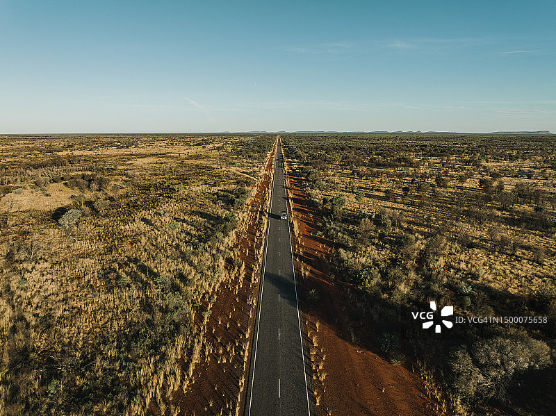 澳大利亚北领地，黄金时段，一辆越野车在柏油路上驶过荒野图片素材