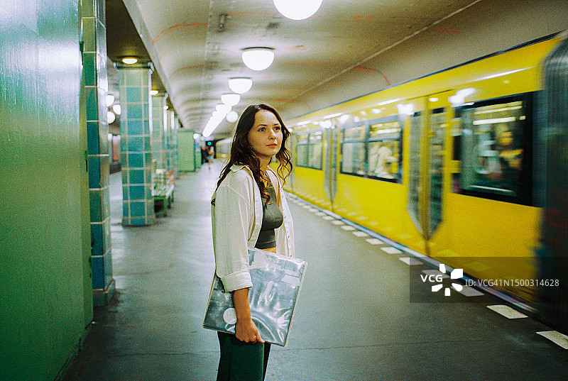 拿着黑胶唱片在车站等地铁的女人图片素材