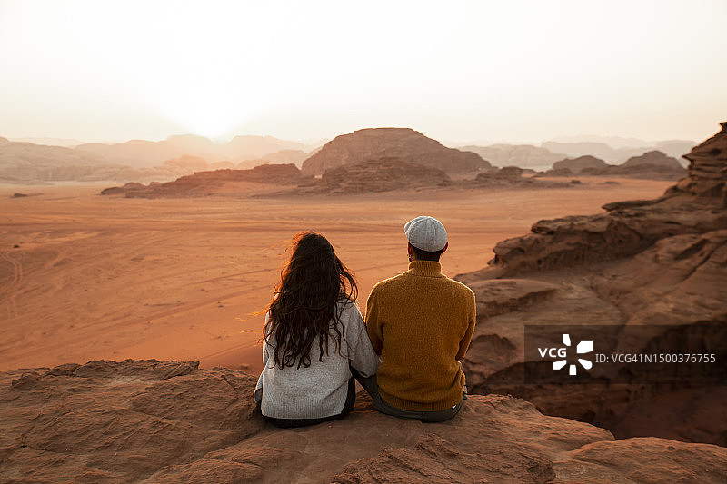 一对夫妇坐在岩石上看日落图片素材
