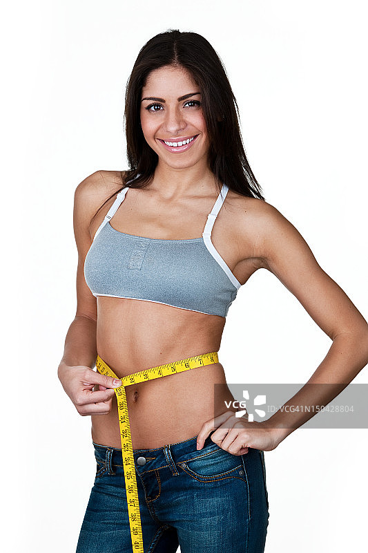 快乐的女人在测量她的腰围图片素材