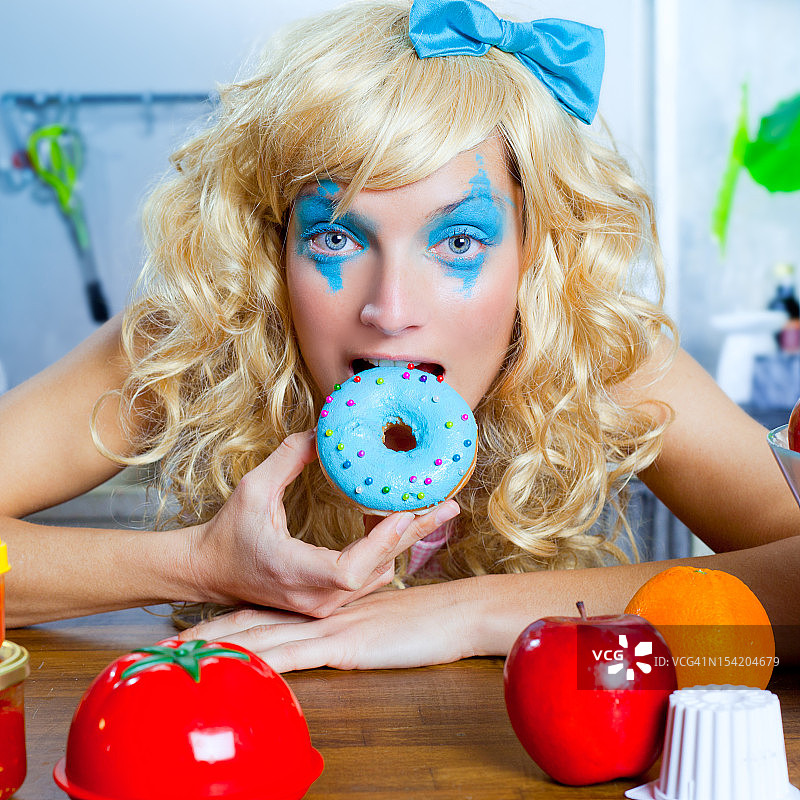 有趣的金发女孩在厨房吃蓝色的多娜图片素材
