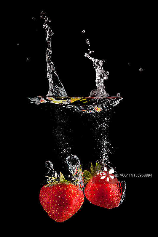 两个草莓在黑色背景上飞溅图片素材