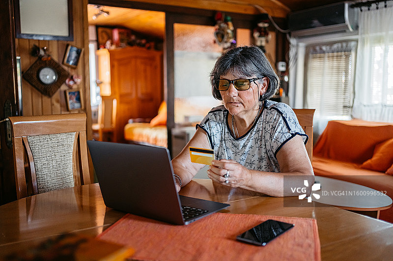 老年妇女在家用笔记本电脑网购图片素材