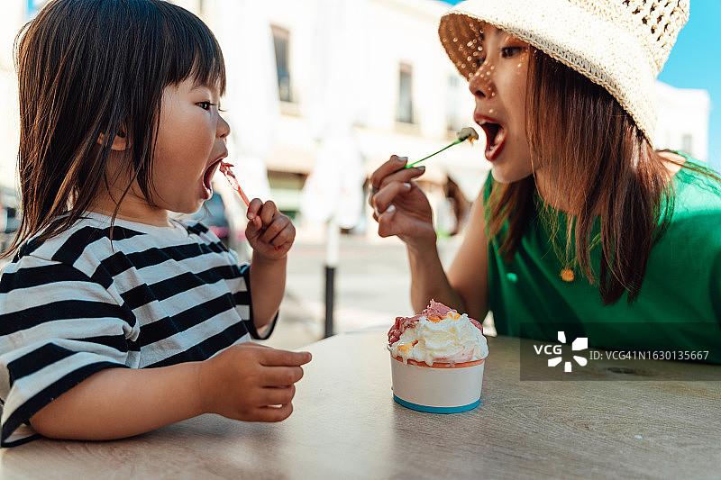 年轻的亚洲母亲在咖啡馆和她的小女儿分享冰淇淋图片素材