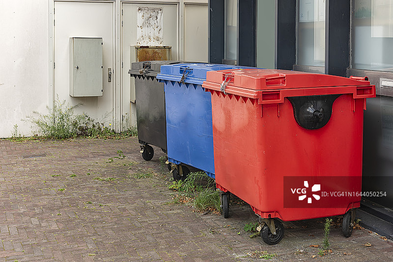 黑色、蓝色和红色的塑料废物容器，盖子是封闭的图片素材
