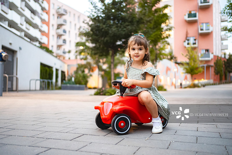 一个小女孩坐在户外的玩具车上图片素材