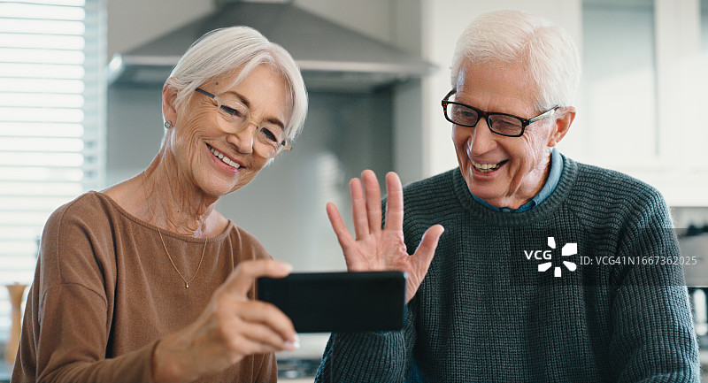 视频通话，电话和老夫妇在家里用手势交流为你好。快乐，微笑和退休的老男人和女人在厨房用手机聊天。图片素材