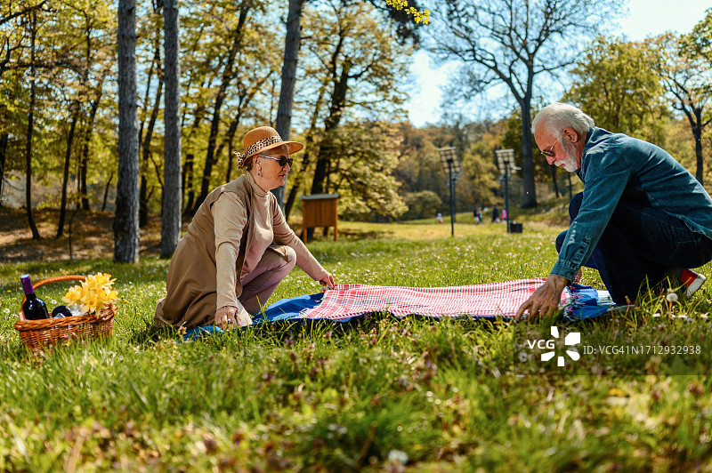一对老年夫妇在公园里铺毯子图片素材