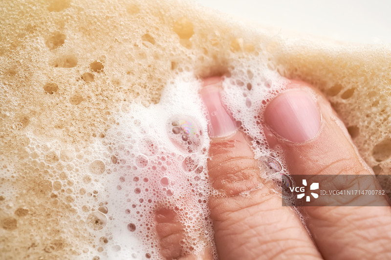 手指挤压泡沫的肥皂海绵。图片素材
