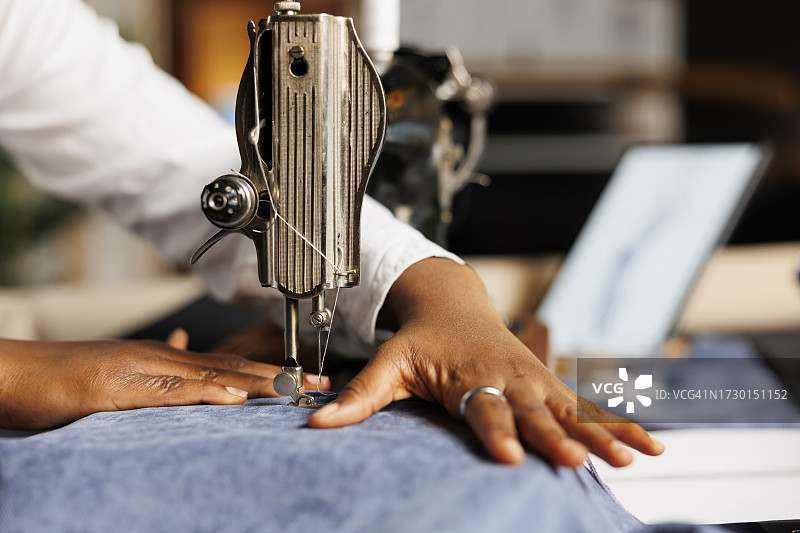 在机器上缝制纺织品的妇女剪短的手图片素材