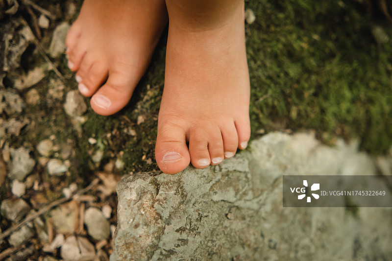 孩子们光着脚踩在铺满绿草和石头的地上图片素材