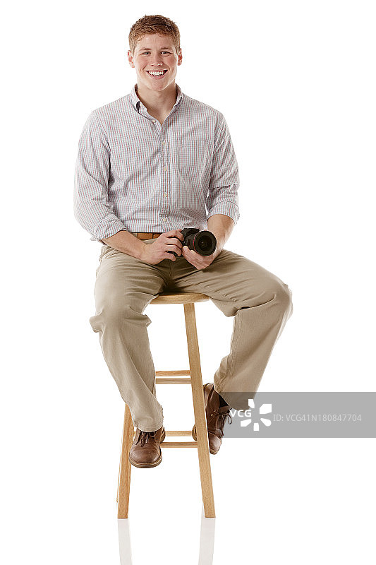 带着相机坐在凳子上微笑的男人图片素材