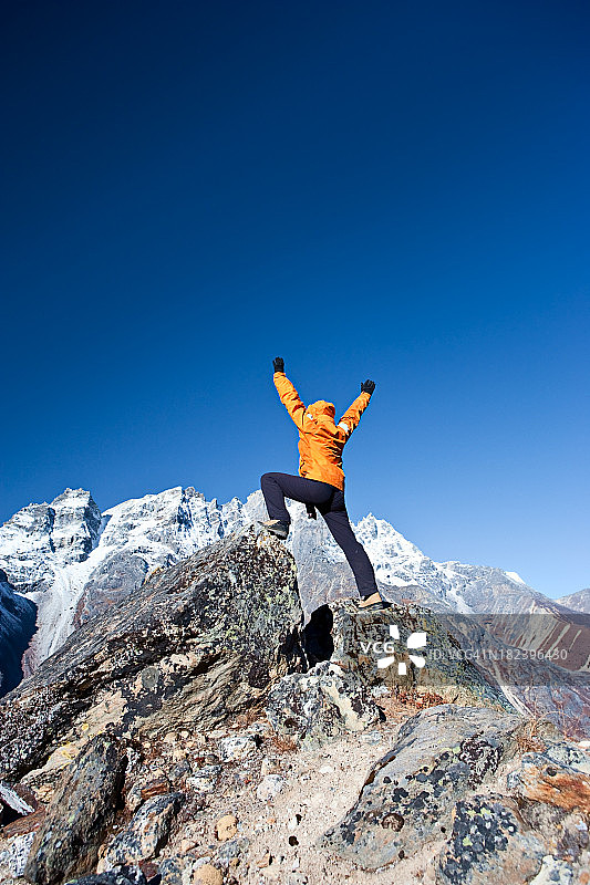 喜马拉雅山脉，一位女性登山者举起她的手臂表示胜利图片素材