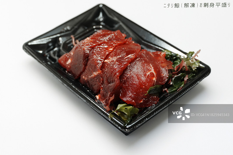白色背景的一次性塑料托盘上的小须鲸生鱼片，在复制空间上添加了日文标题图片素材