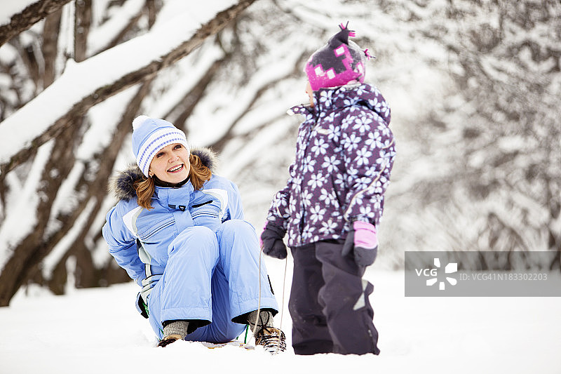 母亲和女儿在冬季公园玩得开心图片素材