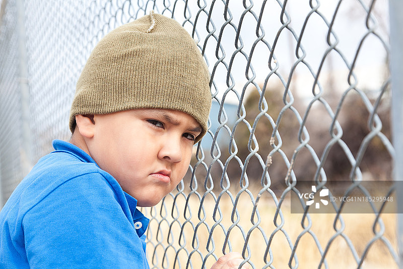 一个小男孩在篱笆旁心烦意乱图片素材