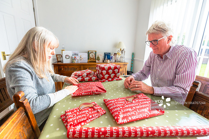 快乐的老年夫妇在家里一起包装圣诞礼物图片素材