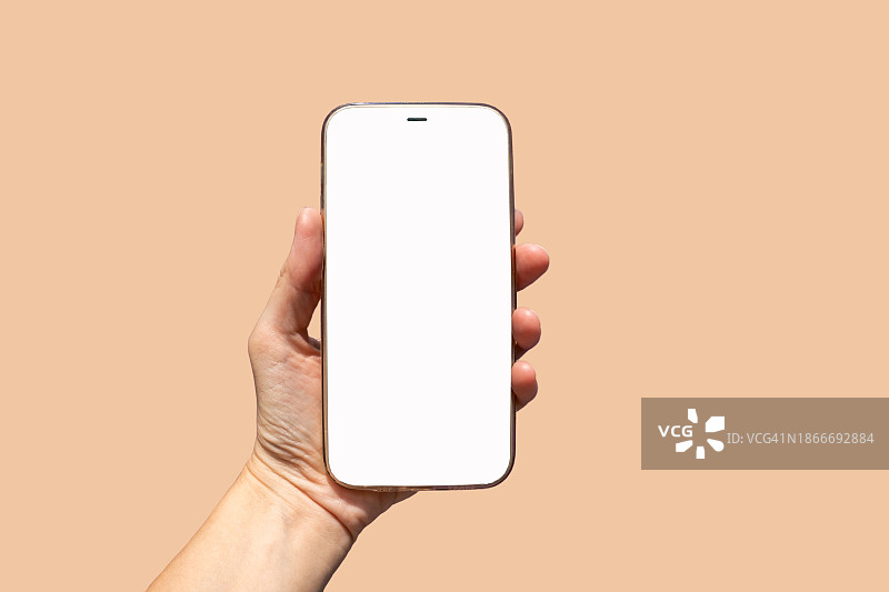 手持白色空白屏幕的智能手机，时尚桃色背景特写。图片素材