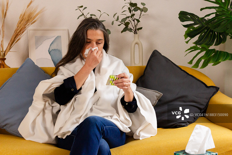 患感冒和流感的生病妇女在家里用纸巾打喷嚏图片素材