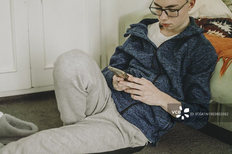 沉迷于社交媒体的青少年坐在地毯上用手机聊天图片素材