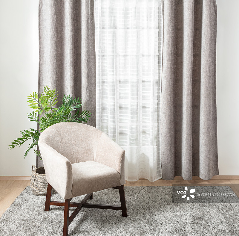 一个白色的现代扶手椅位于窗口附近，在一个空的休息室里有一个浅色的窗帘图片素材