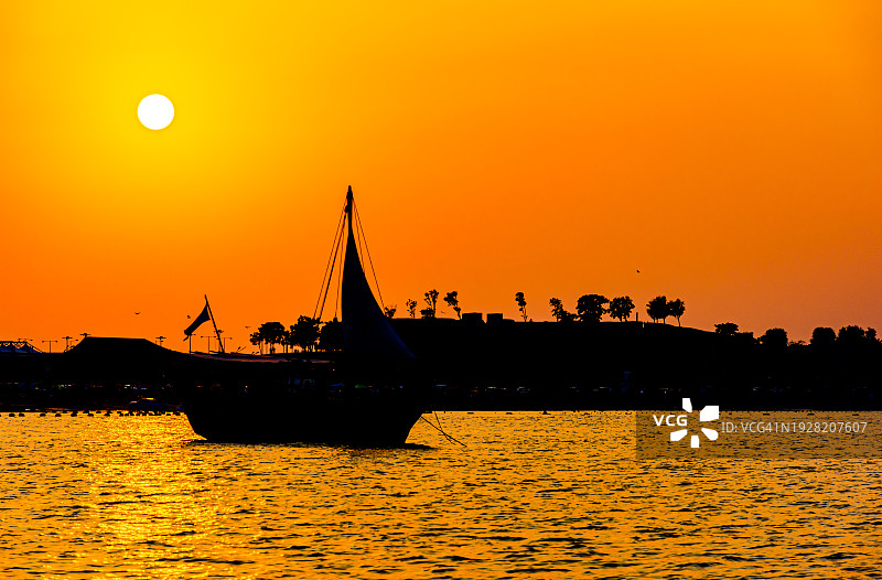 卡塔尔，橙色的天空映衬着海上小船的剪影图片素材