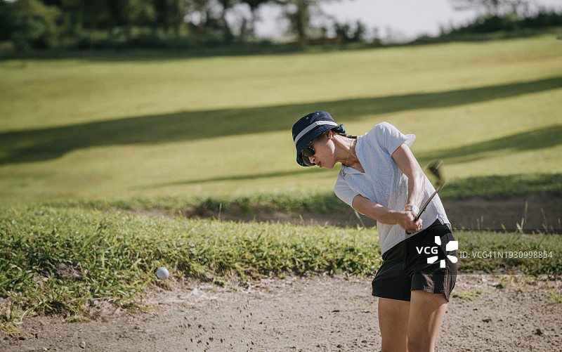 亚洲华人女高尔夫球手在沙坑击球图片素材