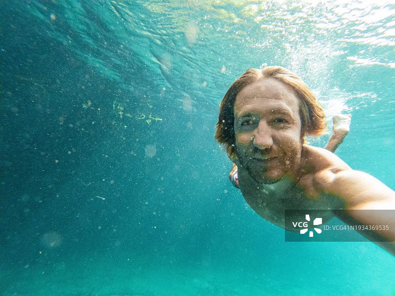 男子在清澈的水中游泳时在水下自拍图片素材