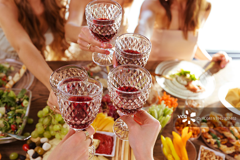 朋友们在餐桌上用酒杯敬酒的高角度照片图片素材