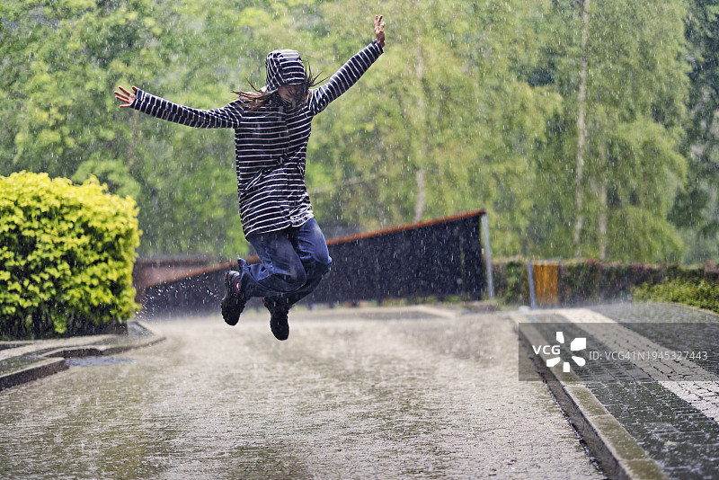 十几岁的女孩在雨中跳跃图片素材