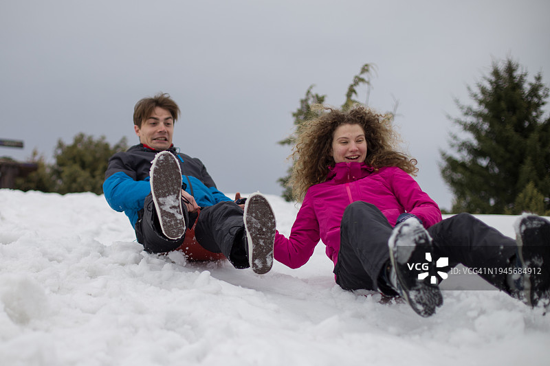 年轻夫妇在下雪天玩雪橇图片素材