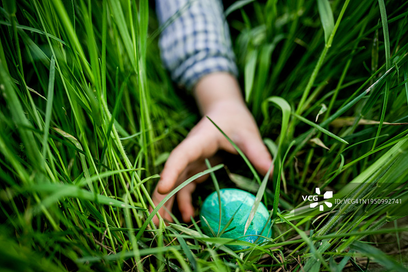 一个小孩伸手去拿复活节彩蛋。图片素材