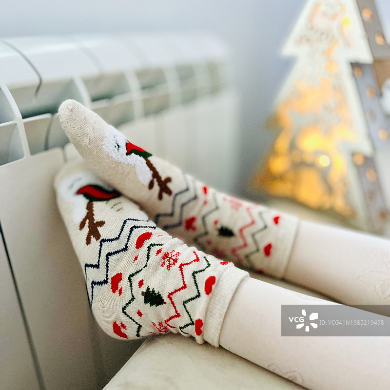 小孩穿着圣诞袜在暖气片上暖脚的特写图片素材
