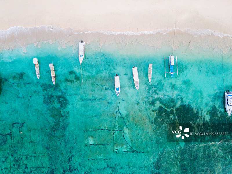 停泊在沙滩附近绿松石水域的船只:努沙佩尼达岛宁静的海岸景观。图片素材