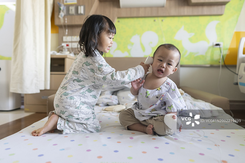 病毒和流感，一名亚洲幼儿在医院里受到一位关心的母亲的悉心照顾。在医疗保健场景中捕捉到的情感支持、医疗关注和家庭弹性图片素材